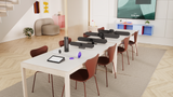 A photo of a meeting room. On the rectangular table are several Logitech video conferencing devices. Beginning nearest the viewer, these products are: Logitech Tap, Logitech Scribe, Logitech Sight, Logitech Rally Bar Huddle, Logitech Rally Bar Mini, Logitech Rally Bar and a Logitech Rally Camera flanked by two Logitech Rally Speakers.